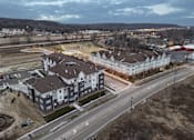 Thumbnail 9 of 11 - A large apartment complex is surrounded by a road and a field.