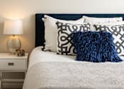 Thumbnail 11 of 24 - A bed with a white comforter and a blue pillow with a black pattern.