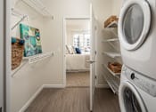 Thumbnail 22 of 24 - A white washing machine is in a laundry room with a door open.