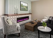 Thumbnail 2 of 24 - A grey chair is in front of a fireplace in a room.