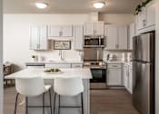 Thumbnail 9 of 24 - A modern kitchen with white cabinets and a center island.