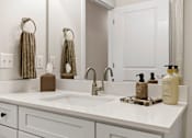 Thumbnail 11 of 25 - A bathroom with a white sink and a white counter.