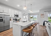 Thumbnail 7 of 15 - A modern kitchen with a large island and stainless steel appliances.