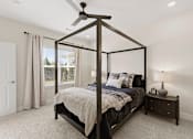 Thumbnail 7 of 25 - A bedroom with a four poster bed and a nightstand with a lamp.