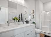 Thumbnail 11 of 19 - A white bathroom with a sink, mirror, toilet, and shower.