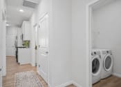 Thumbnail 10 of 43 - a white laundry room with washer and dryer and a door to a kitchen