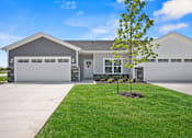 Thumbnail 2 of 19 - A house with a grey garage door and a tree in front.