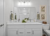 Thumbnail 9 of 19 - A white bathroom with a double sink and a toilet.