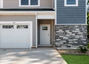 Thumbnail 4 of 62 - A house with a white garage door and a stone wall.