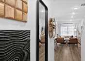 Thumbnail 22 of 62 - A modern living room with a wooden wall art and a mirror reflecting the room.