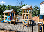 Thumbnail 28 of 62 - A playground with a wooden swing set and a blue slide.