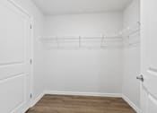 Thumbnail 46 of 62 - A white closet with a wooden floor and a white door.