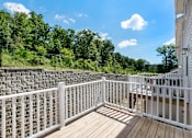 Thumbnail 49 of 62 - A white railing on a wooden deck overlooks a forest.