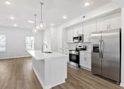 Thumbnail 51 of 62 - A modern kitchen with stainless steel appliances and wooden floors.