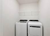 Thumbnail 57 of 62 - Two white front load washing machines in a laundry room.