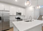 Thumbnail 11 of 62 - A modern kitchen with a white countertop and stainless steel appliances.