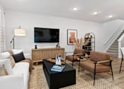 Thumbnail 15 of 62 - A living room with a white couch, a black coffee table, and a television.