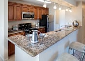 Thumbnail 9 of 49 - A kitchen with granite countertops and wooden cabinets.