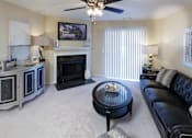 Thumbnail 2 of 49 - A living room with a black leather couch, a fireplace, and a ceiling fan.