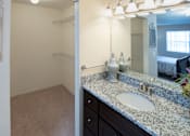 Thumbnail 14 of 49 - A bathroom with a sink, mirror, and a bed in the background.