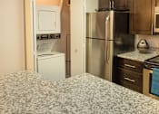 Thumbnail 18 of 49 - A kitchen with a refrigerator, oven, and microwave.