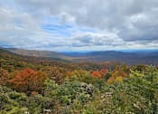Thumbnail 15 of 15 - A landscape image of a mountain range with autumn trees in the foreground.