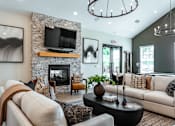 Thumbnail 16 of 29 - A living room with a stone fireplace and a television above it.