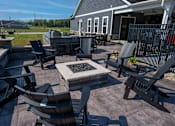 Thumbnail 22 of 29 - A patio with a fire pit and chairs.