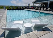 Thumbnail 21 of 29 - A pool with white chairs and a white toilet in the middle.