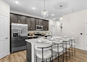 Thumbnail 26 of 39 - A modern kitchen with a large island and stools.