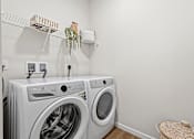 Thumbnail 27 of 39 - A white washing machine and dryer in a laundry room.