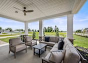 Thumbnail 32 of 39 - A patio with a couch, chairs, and a ceiling fan.