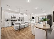 Thumbnail 3 of 39 - A modern kitchen with white cabinets and a dining table with chairs.