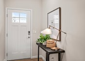 Thumbnail 16 of 39 - A white door is on the left of a table with a lamp and a plant on it.