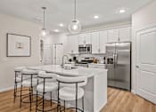 Thumbnail 2 of 39 - A modern kitchen with white cabinets and a central island.