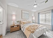 Thumbnail 10 of 19 - A bedroom with a large bed and a ceiling fan.
