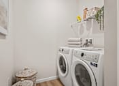 Thumbnail 14 of 39 - A white laundry room with a washer and dryer stacked on top of each other.