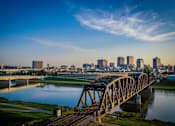 Thumbnail 19 of 19 - A bridge spans a river with a city skyline in the background.