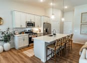 Thumbnail 2 of 29 - A kitchen with a white island and wooden chairs.