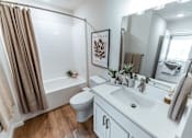 Thumbnail 11 of 29 - A bathroom with a white sink, toilet, and a brown shower curtain.