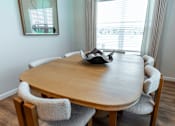 Thumbnail 9 of 29 - A round wooden table with a hat on it and chairs around it.