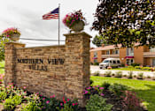 Thumbnail 12 of 13 - A sign for Northern View Villas is surrounded by flowers and an American flag.