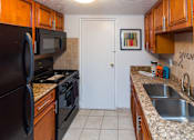 Thumbnail 1 of 13 - A kitchen with a black refrigerator, black microwave, black oven, and a white door.