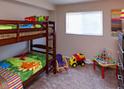 Thumbnail 7 of 13 - A child's bedroom with bunk beds, a toy truck, and a table with toys.