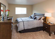 Thumbnail 5 of 13 - A bedroom with a bed, nightstand, and a dresser.