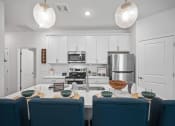 Thumbnail 4 of 17 - a kitchen with white cabinets and a table with blue chairs