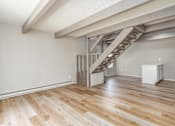 Thumbnail 14 of 27 - A room with wooden flooring and a staircase.