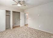 Thumbnail 18 of 27 - A room with a ceiling fan and carpeted floor.