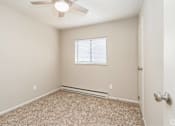Thumbnail 20 of 27 - A room with a ceiling fan and carpeted floor.
