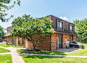 Thumbnail 26 of 27 - A brick house with a tree in front.
